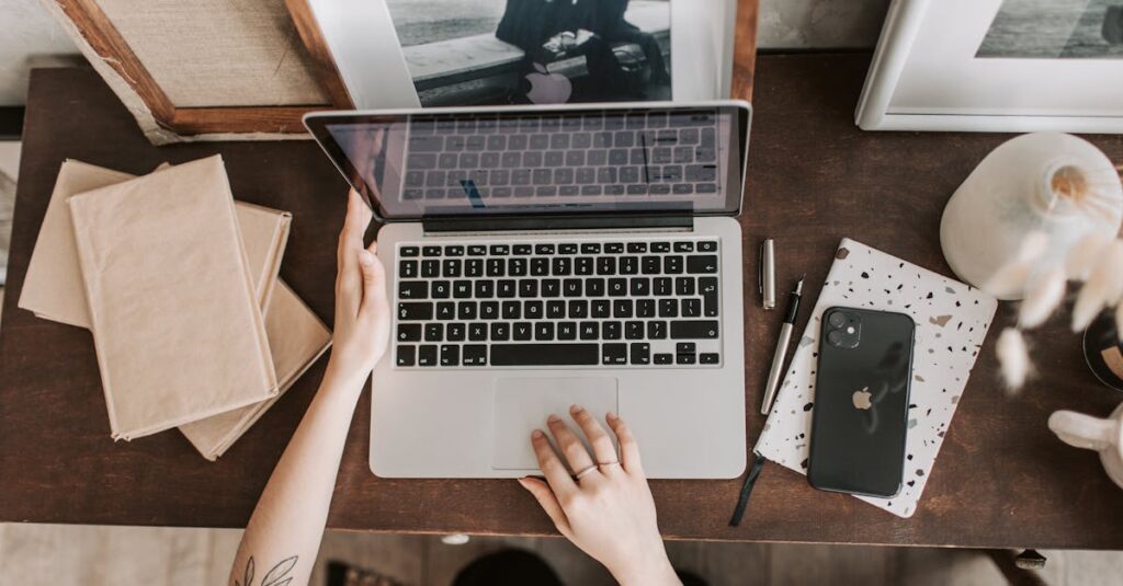 An aesthetic workspace featuring a laptop, smartphone, and stationery items from a top-down view.